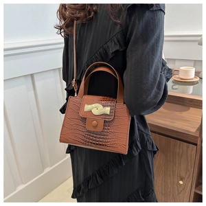 Détail de la texture crocodile marron et du fermoir en métal doré sur le sac à main de luxe