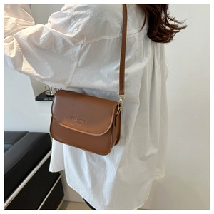 Detail of vintage brown crossbody bag featuring gold metal buckle and embossed brand logo