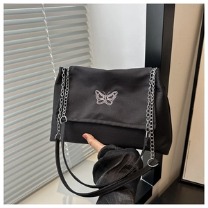 Detail of butterfly embroidery on black canvas shoulder bag with silver metal chain