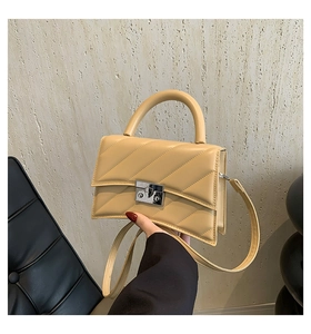 Détail d'un sac bandoulière crème avec surpiqûres en V et fermoir rectangulaire argent
