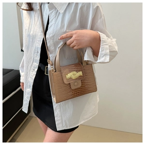 Détail de la texture crocodile et boucle dorée ondulée sur ce sac à bandoulière marron