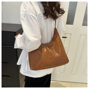 Close-up of brown oiled leather shoulder bag featuring vertical stitching and a semi-lune shape