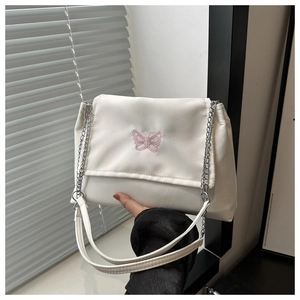 Close-up of pink butterfly embroidery on white chain shoulder bag with metal details
