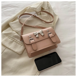 Vue détaillée du petit sac bandoulière rose avec nœud métallique et smartphone