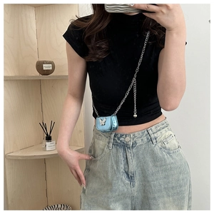 Mirror selfie showing a mini metallic blue crossbody bag with a silver butterfly accent
