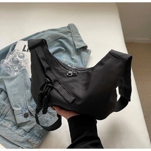 Detail of black nylon crescent bag showing water-resistant fabric and side woven ropes