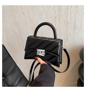 Détail du sac à main noir matelassé montrant le fermoir en métal argenté et la poignée