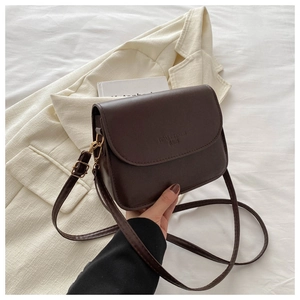Detailed view of the dark brown leather shoulder bag with embossed lettering and gold buckle
