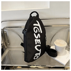 Détail du sac bandoulière noir streetwear avec texte TGSEUTO blanc sur chaise en métal