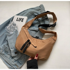 Detail of khaki nylon crescent tote bag with wide black strap and urban lifestyle props