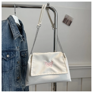Detail view of the pink butterfly embroidery on a white chain strap shoulder bag