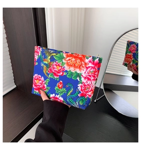 Dettaglio ravvicinato di una pochette in nylon blu con motivi tradizionali di peonia e fenice