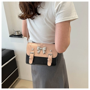 Détail d'un sac bandoulière rose et noir avec noeud métallique sur un mannequin