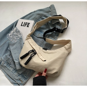 Close-up of beige nylon crescent bag with adjustable strap and dual zipper details