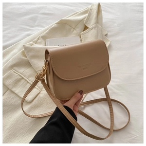 Detail shot of a minimalist beige matte leather crossbody bag with flap and lettering