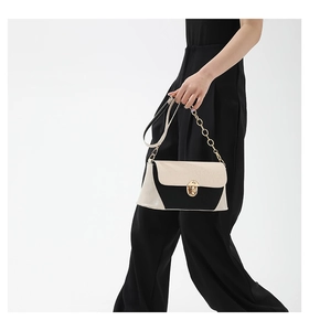 Detail view of contrast color baguette bag with crocodile pattern and golden chain
