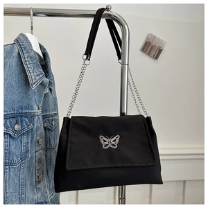 Detail of white butterfly embroidery and chain strap on black canvas shoulder bag
