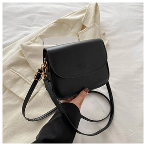 Detail of minimalist black leather crossbody bag with gold metal buckle and embossed text