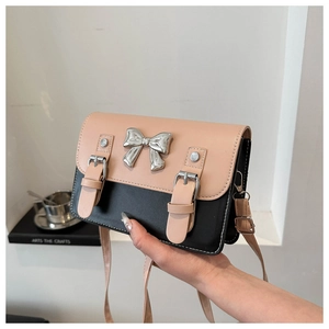 Vue détaillée du sac bandoulière rose et noir avec nœud argenté et lanières cuir