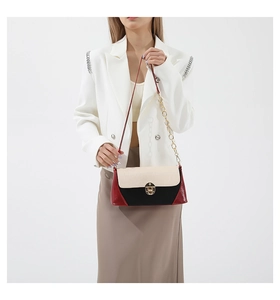 Detail of color-block baguette bag with crocodile texture flap and gold metal buckle