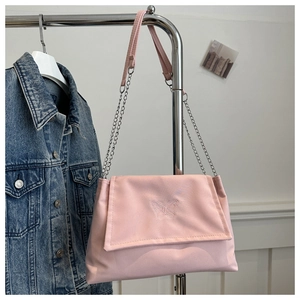 Detail of pink canvas shoulder bag featuring butterfly embroidery and chain strap