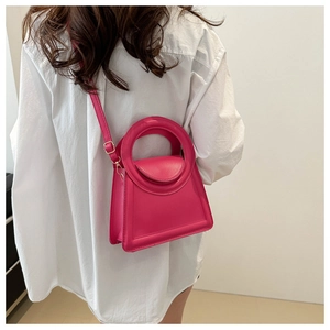 Detailed view of magenta PU leather crossbody bag with circular cutout handle and flap cover