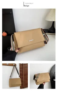 Detailed view of brown pebble leather tote bag featuring a striped wide fabric strap
