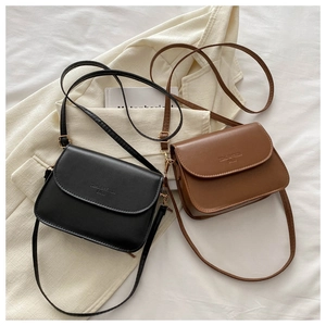 Detail of vintage flap crossbody bags in black and brown PU leather on a fabric background