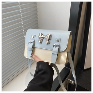 Détail du sac bandoulière bleu et beige avec nœud argenté et bandoulière réglable