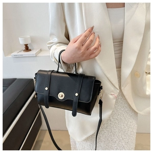 Detailansicht der schwarzen Lederhandtasche mit goldenem Drehverschluss an einem Modell
