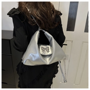 Close-up of silver crescent hobo bag with a metallic bow buckle and chain strap