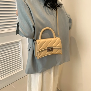 Sac bandoulière beige matelassé avec base incurvée et boucle métallique pour femmes