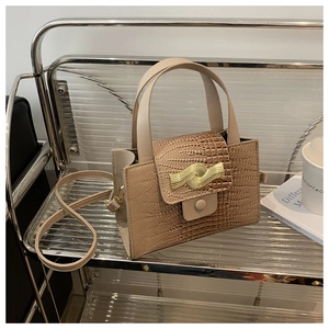 Détail du sac marron clair à texture crocodile avec boucle en métal doré ondulée