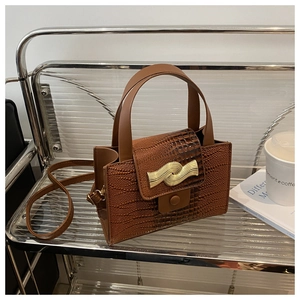 Détail du sac à main marron foncé avec gaufrage crocodile et fermoir doré élégant