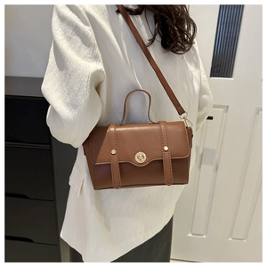Braune Retro-Tasche mit goldenem Drehverschluss und zwei Lederriemen im Detail