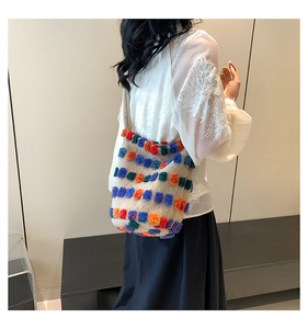 Detail view of cream plush bucket bag featuring vibrant multi-colored faux fur pom-poms