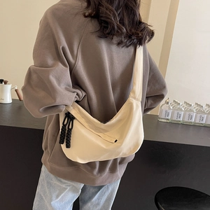 Minimalist beige moon bag with contrast black braided zipper in a casual daily look