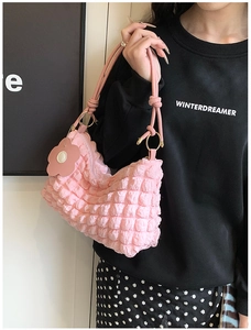 Detail of pink popcorn textured shoulder bag with floral charm and gold metal rings