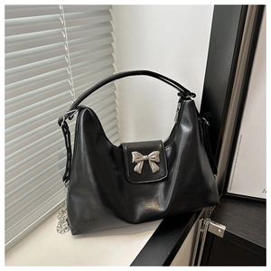 Detail of black hobo bag with metallic silver bow and decorative side chain texture