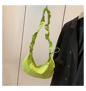 Détail du sac demi-lune vert citron avec bandoulière plissée et coutures géométriques