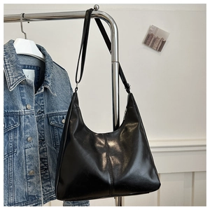 Detail of a black crescent shoulder bag featuring smooth PU leather and vertical stitching