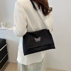 Minimalist black canvas shoulder bag with butterfly embroidery and silver chain strap