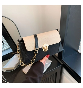 Detailed view of the gold circular twist lock and white croc-embossed flap on a leather bag