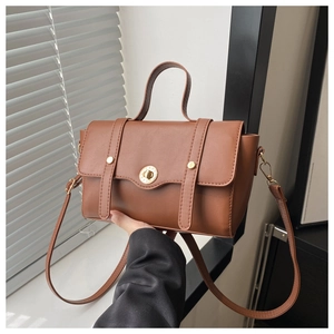 Detailansicht der braunen Ledertasche mit goldenem Drehverschluss und Griffstruktur