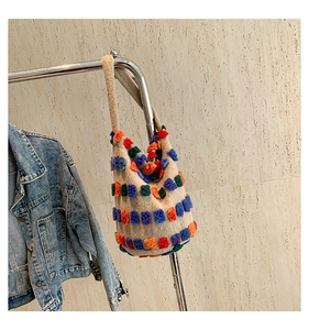 Detail of plush bucket bag with colorful square patterns hanging on a silver rack
