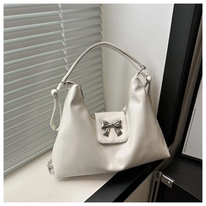 Detail of a creamy white hobo bag featuring a silver metal bow buckle and chain accents