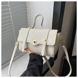 Detailansicht der cremefarbenen Kunstledertasche mit goldenem Drehverschluss und Nieten