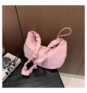 Vue détaillée du sac nuage rose avec bandoulière froncée sur une surface boisée