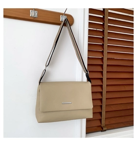 Detail of beige pebbled leather crossbody bag featuring a tricolor woven wide shoulder strap