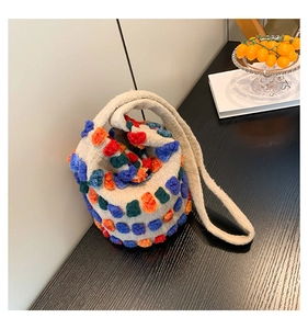Detail of plush knit bucket bag with colorful polka dots on warm wooden table